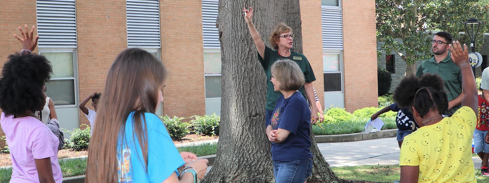 Dr. 林恩·胡克斯特拉站在树前，为卡罗莱纳大学的学生讲授自然知识. 